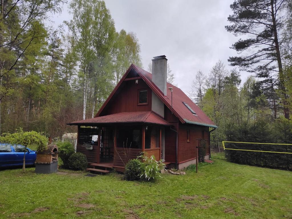 a small red house in the middle of a field at Klimatyczny domek w lesie przy jeziorze in Gietrzwałd