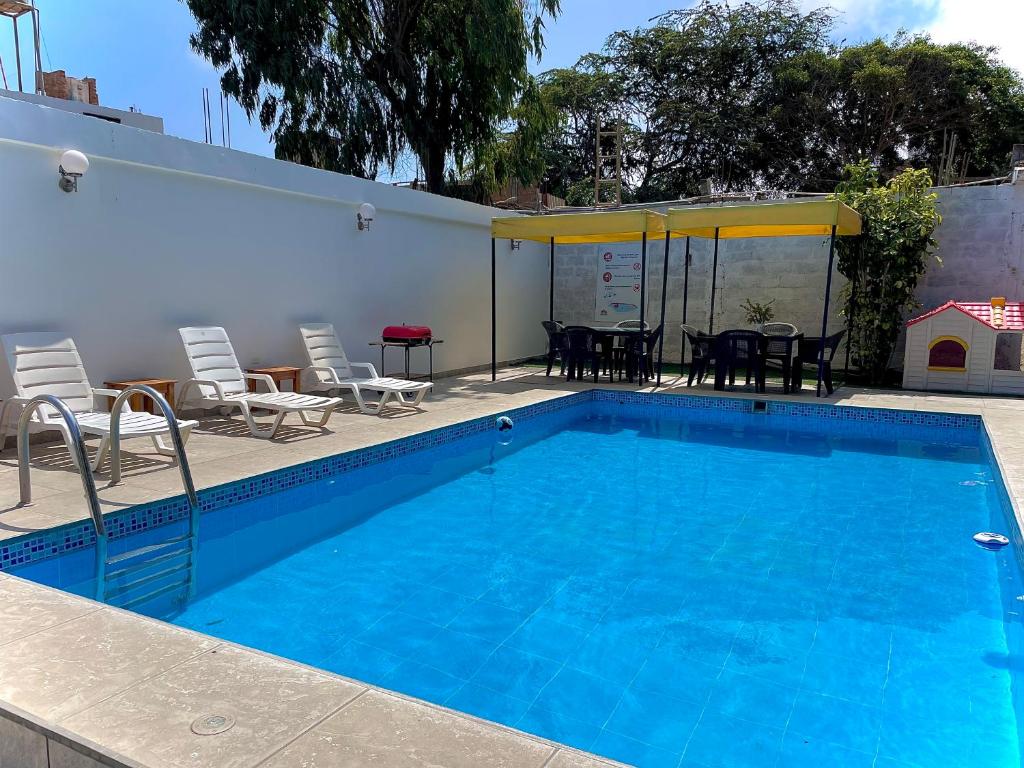 Una gran piscina azul con sillas y una mesa. en HUANCHACO GARDENS, en Huanchaco