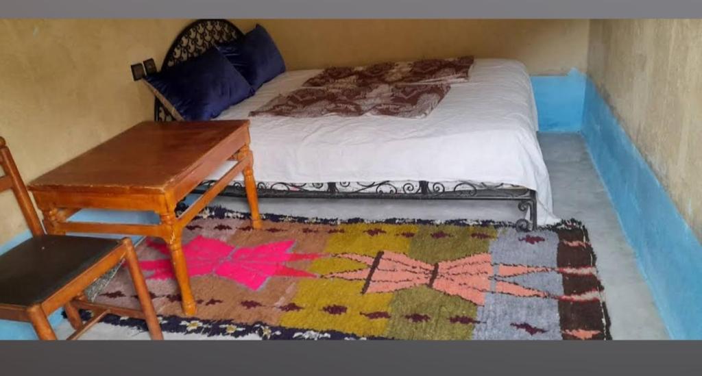 1 dormitorio con 1 cama, escritorio y mesa en Auberge amouger assoul en Aït el Hami