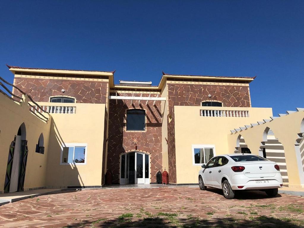 a white car parked in front of a building at sidi kaouki ayt karoum in Sidi Kaouki