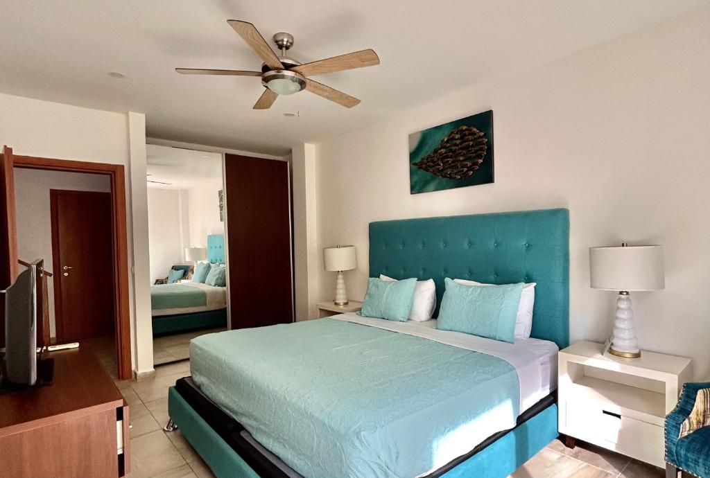 1 dormitorio con 1 cama azul y ventilador de techo en Habitación privada en Dixon Cove Roatan, en Roatan