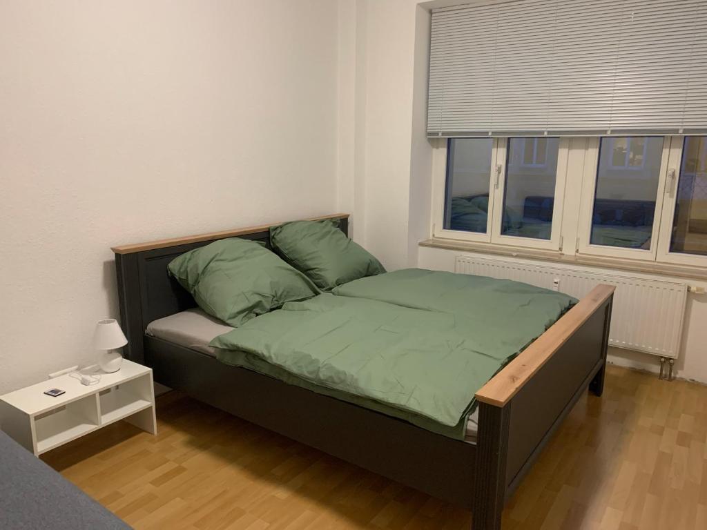 um quarto com uma cama com lençóis verdes e uma janela em Ferienwohnung für kleine und große Reisegruppe em Dresden
