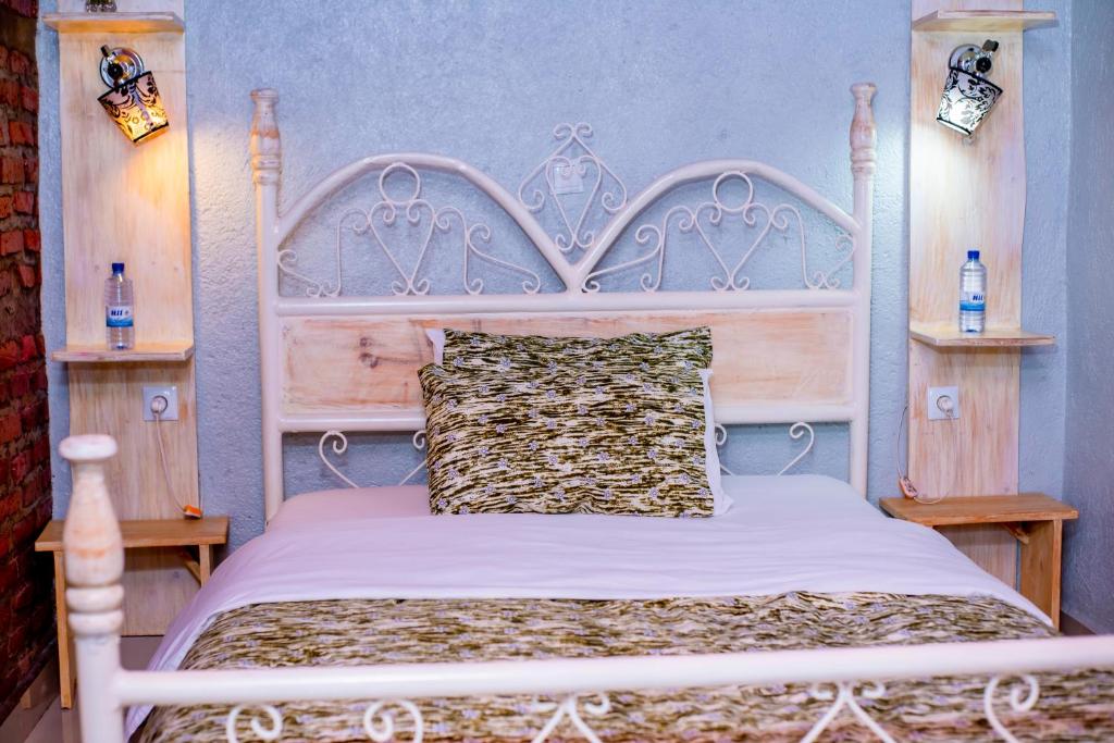 a bedroom with a white bed with a wooden headboard at Little Birds Paradise in Ruhengeri