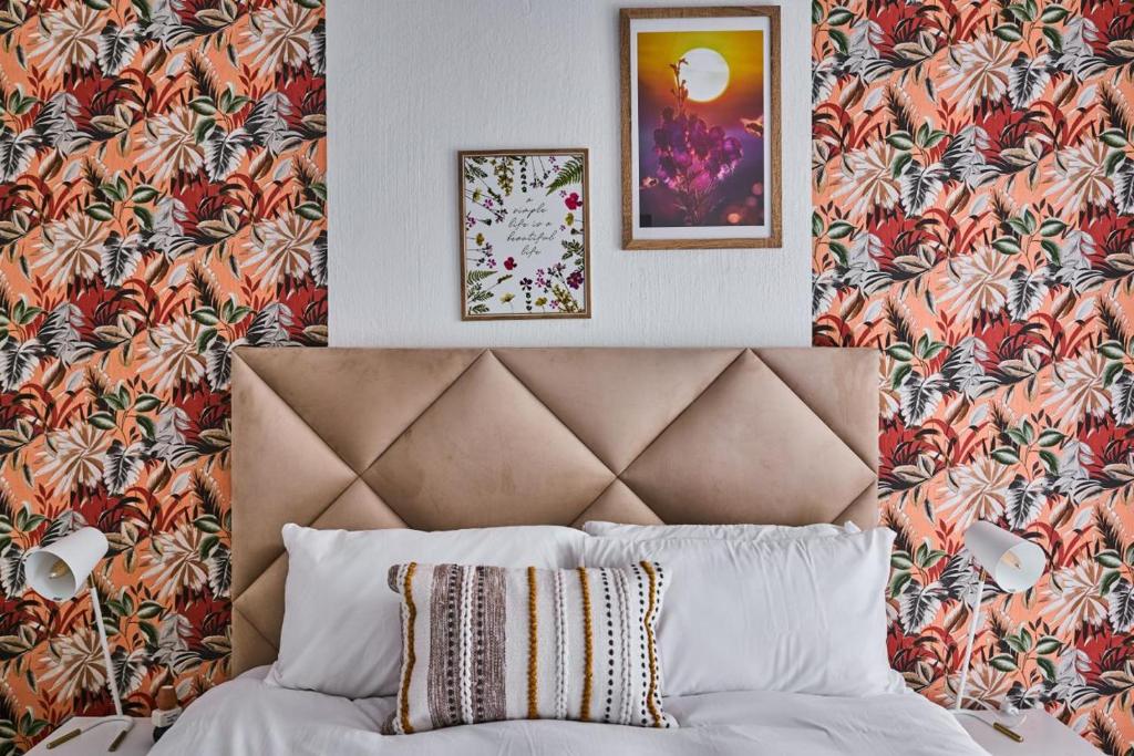- une chambre avec un lit et du papier peint fleuri dans l'établissement Karabo's Nest, à Johannesbourg