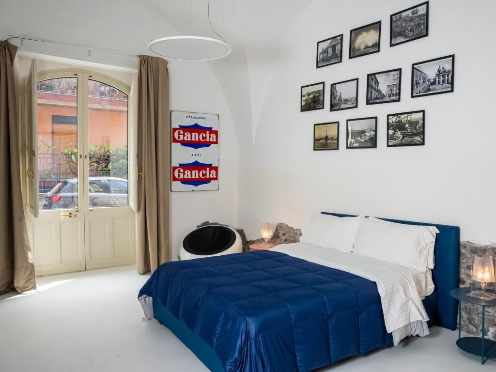 a bedroom with a blue bed and pictures on the wall at Pescheria Industriale in Riposto