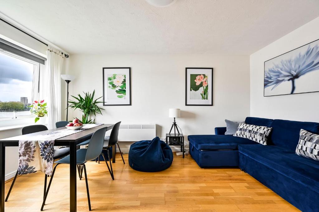 a living room with a blue couch and a table at River views from Canary Wharf in London
