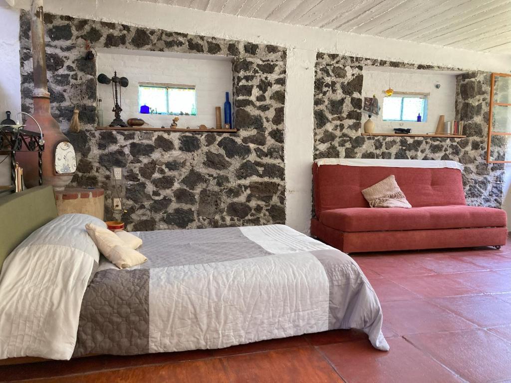 een slaapkamer met een bed en een rode bank bij Loft panorámico en Tepoztlan in Morelos