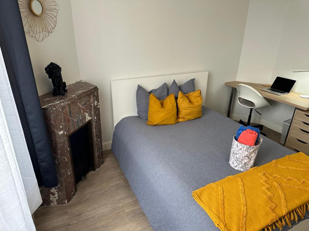 a bedroom with a bed with yellow pillows and a desk at Les Jardins Des Chambrettes in Clermont-Ferrand