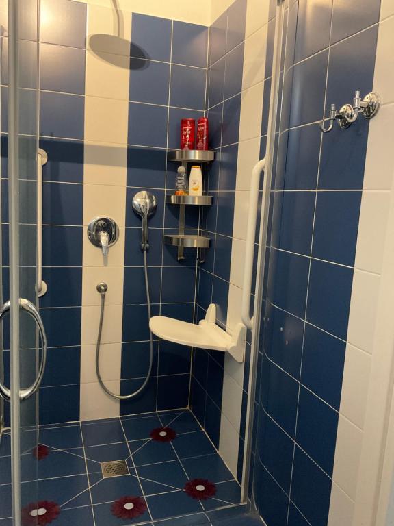 La salle de bains est pourvue de carrelage bleu, d'une douche et d'un lavabo. dans l'établissement NONPERTUTTI PIAZZA CASTELLO Senior e famiglie TOP, à Turin