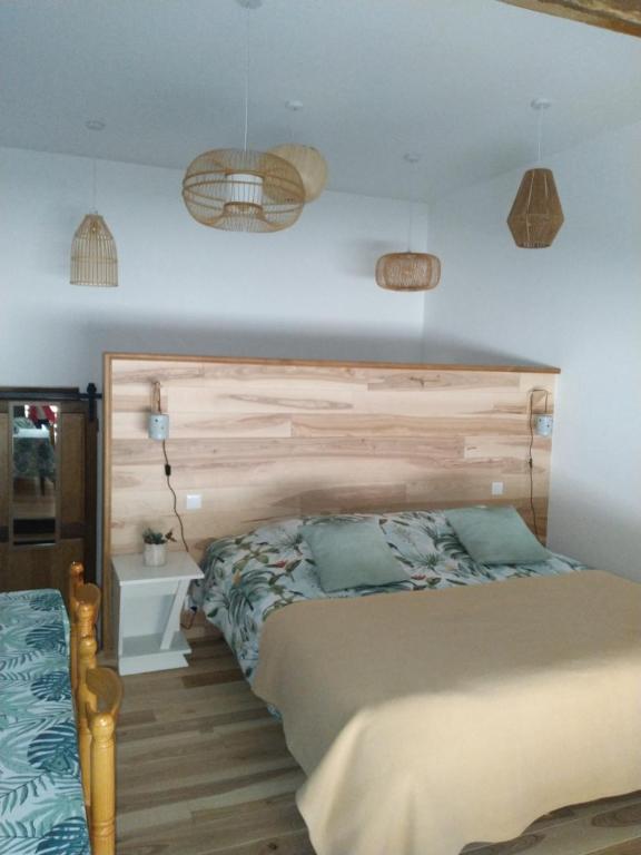 1 dormitorio con 1 cama con cabecero de madera en A la maison du bonheur, en Lanty-sur-Aube