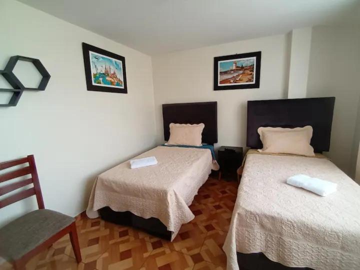 Habitación con 2 camas y silla en A y J Familia Hospedaje, en Lima