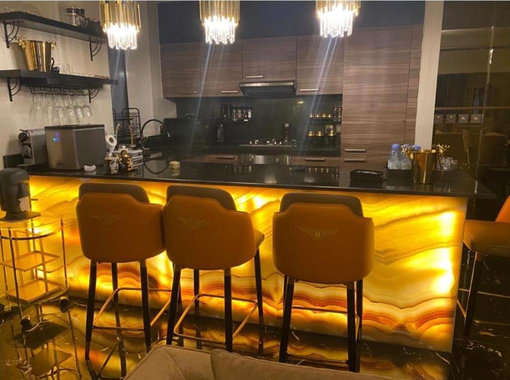 a kitchen with a yellow counter with four bar stools at شقه فندقيه خدمة ٢٤ ساعه باسكوت in Riyadh