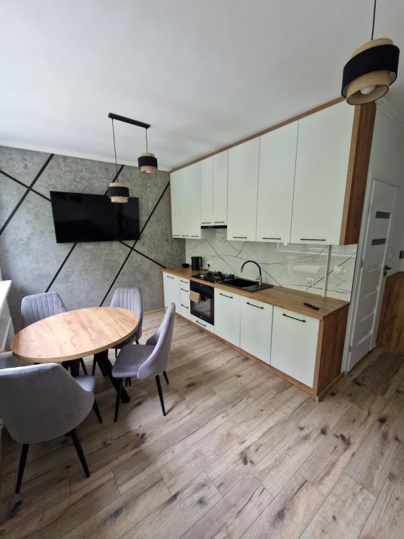 a kitchen with white cabinets and a wooden table at Moniuszko in Lesko