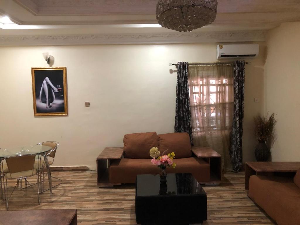 uma sala de estar com um sofá e uma mesa em Dazzle Hotels and Apartments em Jidu
