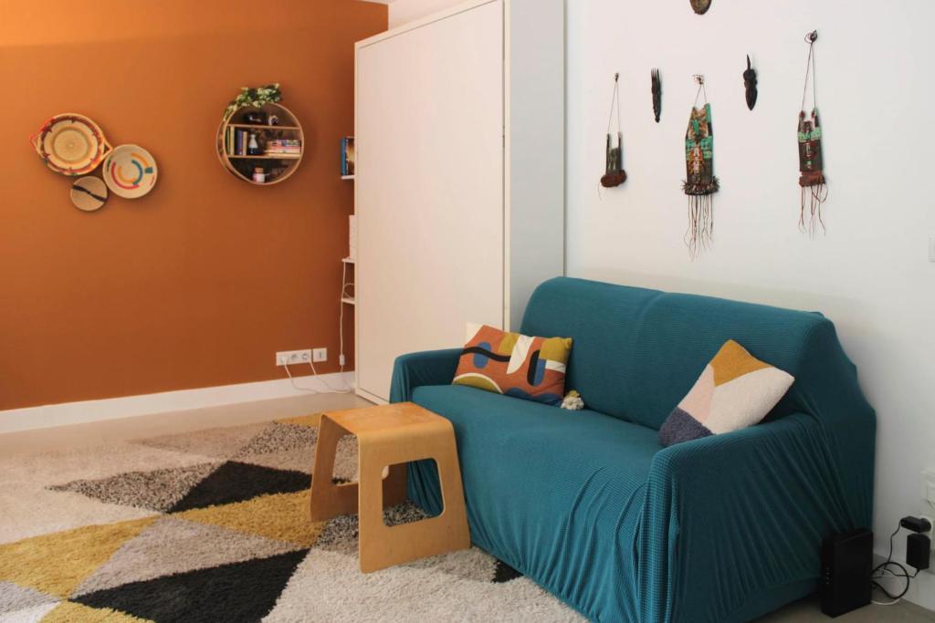 een woonkamer met een blauwe bank en een kruk bij Studio with terrace near Paris in Boulogne-Billancourt