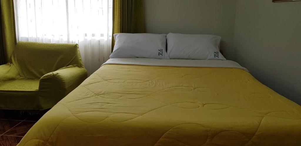 Bett in einem Zimmer mit einem Stuhl und einem Fenster in der Unterkunft Oro Verde Hostal in Cusco