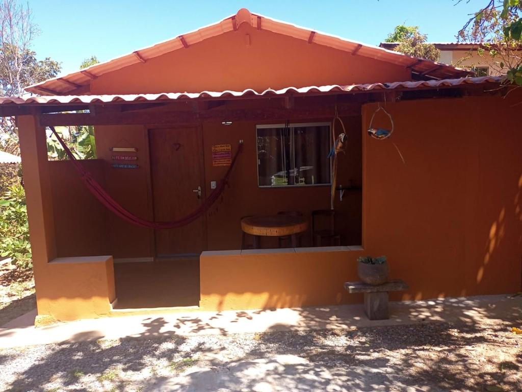 een klein oranje huis met een tafel en een stoel bij viladasararas in Alto Paraíso de Goiás