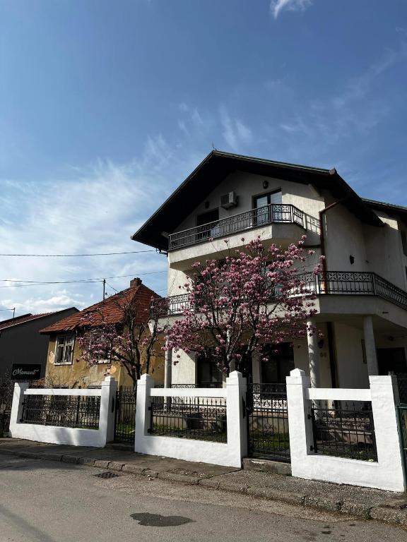 a white house with a fence in front of it at Hostel Tuzla in Tuzla