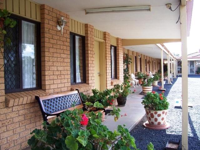 a bench sitting next to a building with potted plants at Three Ways Motel in Gilgandra