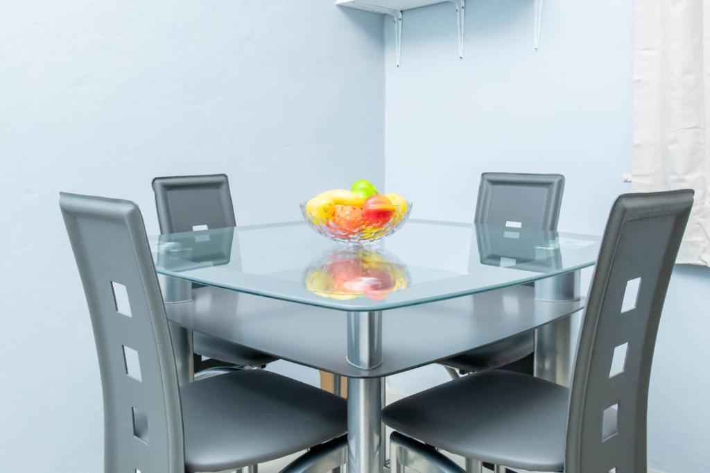 een glazen tafel met stoelen en een kom appels erop bij Christal Sunshine in Boca Pen