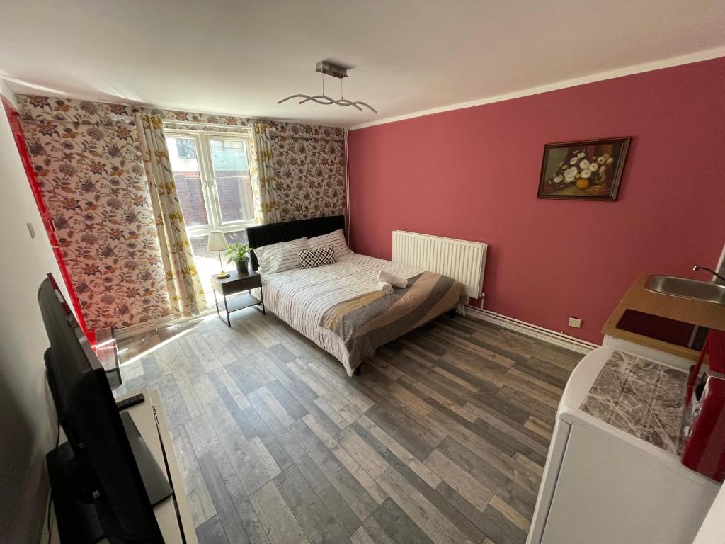 ein Schlafzimmer mit einem Bett und einer roten Wand in der Unterkunft Zen Den Studio #2 in London