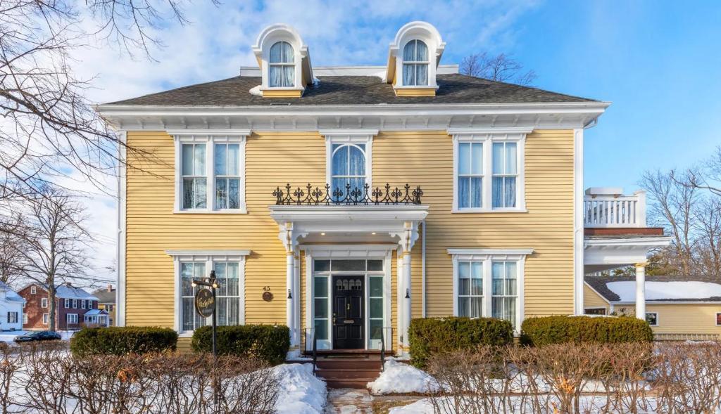 a yellow house with a front door and windows at Fitzroy Hall in Charlottetown