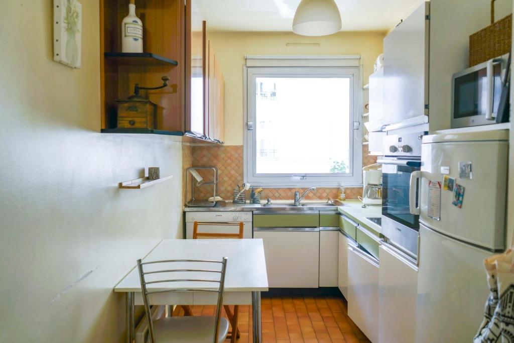 a kitchen with a white refrigerator and a table and a window at Cozy 58 m near Butte-aux-Cailles in Paris