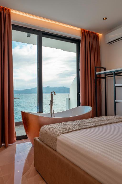 um quarto com uma banheira, uma cama e uma janela em Siro Kerma Private Beach Villa em Sarandë