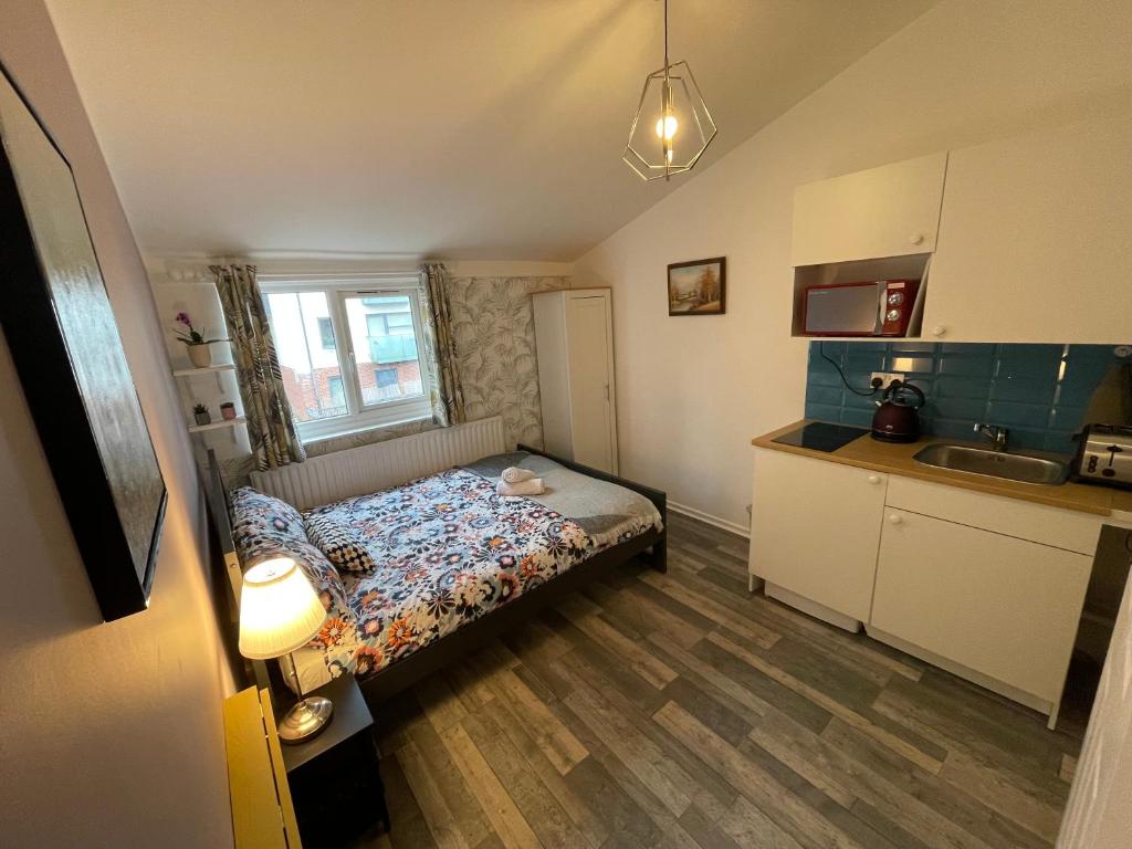 małą sypialnię z łóżkiem i kuchnią w obiekcie City Nest Studio #3 w Londynie