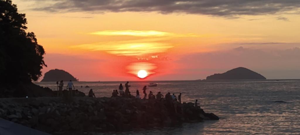 un grupo de personas en la playa al atardecer en Suíte 2 beliches, cozinha e quintal compartilhados, en São Sebastião