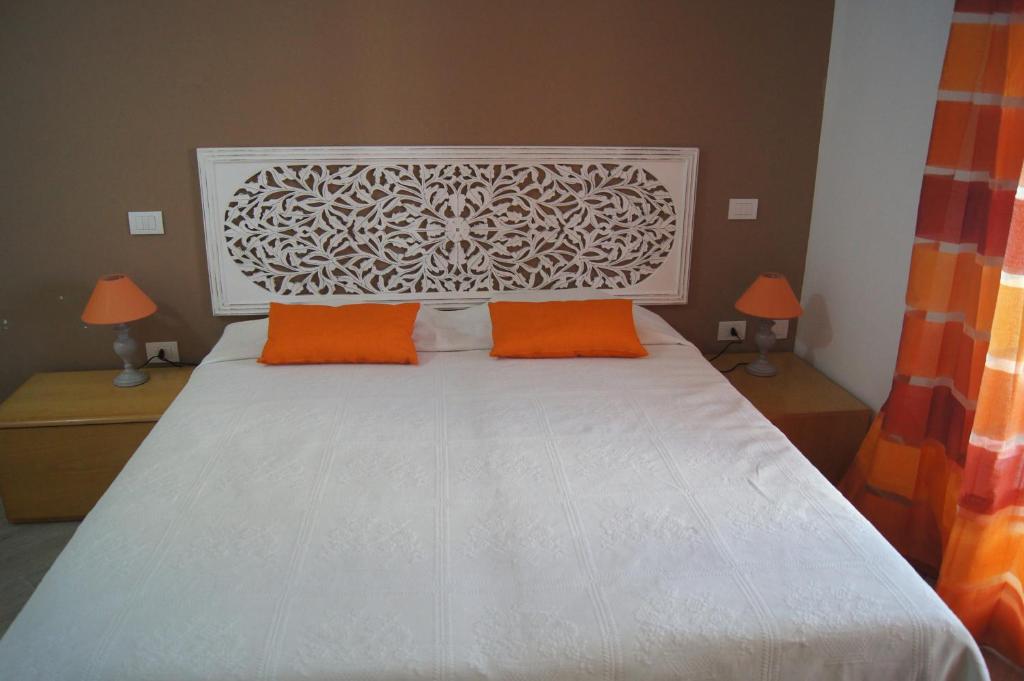 クアルトゥ・サンテーレナにあるLe Villette Di Quartuのベッドルーム1室(白いベッド1台、オレンジ色の枕付)