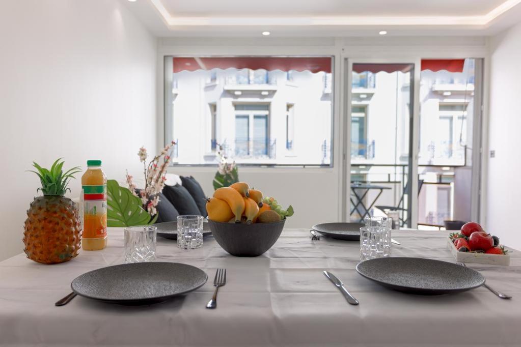 - une table avec des assiettes et un bol de fruits dans l'établissement Lunique Maubourg - Next Hôtel Martinez - terrasse, à Cannes