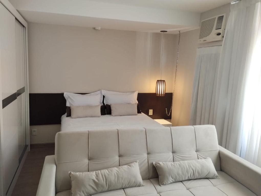a white couch in a bedroom with a bed at UH 1116 Flat Live Logde Vila Mariana in Sao Paulo