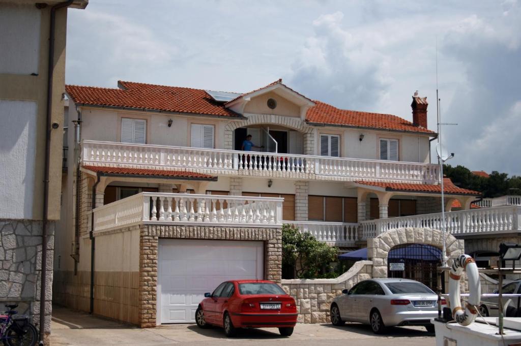 a house with two cars parked in front of it at Apartments by the sea Jezera, Murter - 5123 in Jezera