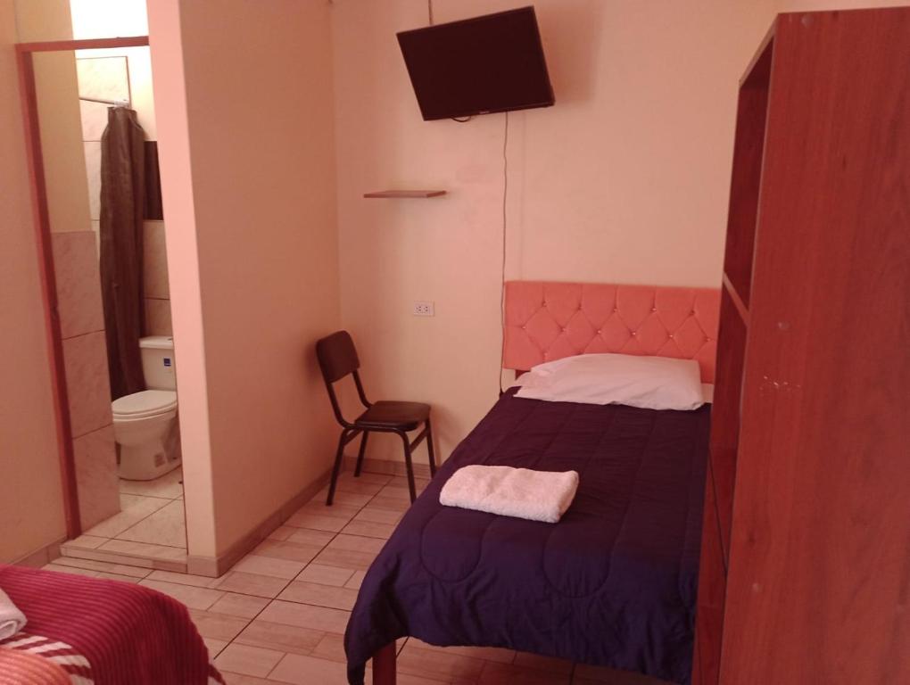 una piccola camera con letto e televisore di Hostal El Conde a Tacna