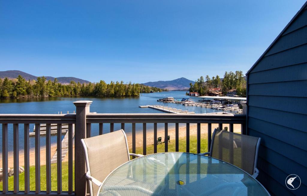 a table and chairs on a balcony with a view of a river at Stunning Lake and Mountain Views, Pool, Beach, Walk to Town! in Lake Placid