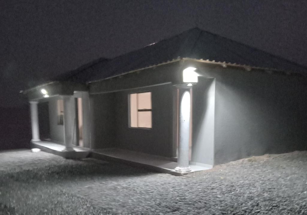 a small house with a light on the side of it at night at Sandton guesthouse in Ga-Manapane