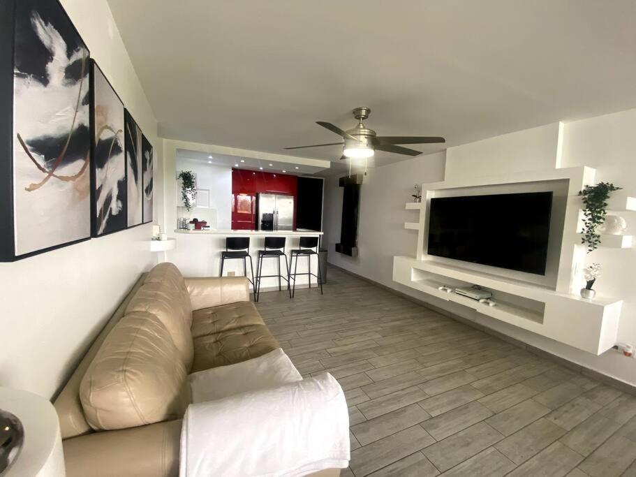 a living room with a couch and a flat screen tv at Beachfront Bliss at Isla Verde in San Juan