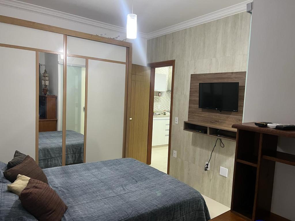 a bedroom with a bed and a tv on a wall at Lindo apartamento em angra dos reis in Angra dos Reis