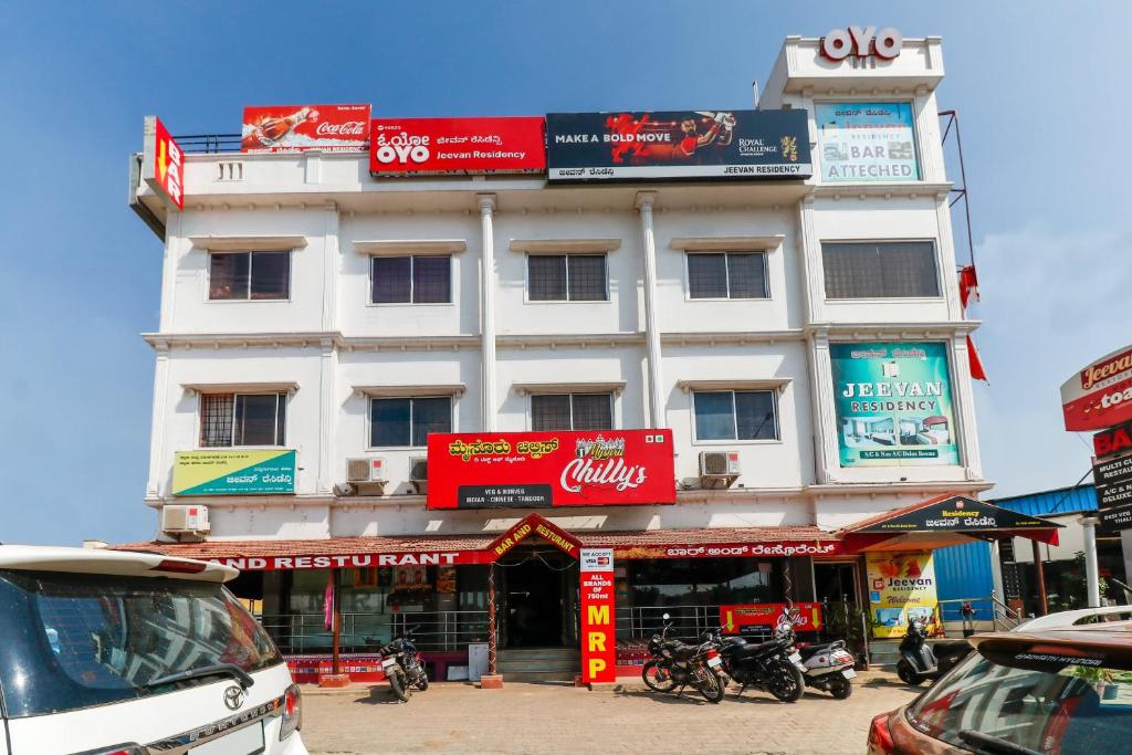 a tall white building with red signs on it at Super OYO 40825 Jeevan Residency in Mysore