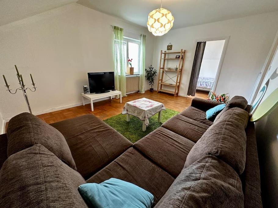 a living room with a brown couch and a tv at Vindsvåning Ljungaverk in Ljungaverk