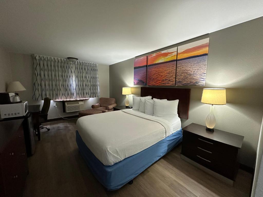 スティーブンスポイントにあるDays Inn & Suites by Wyndham Stevens Pointの大きなベッドとデスクが備わるホテルルームです。
