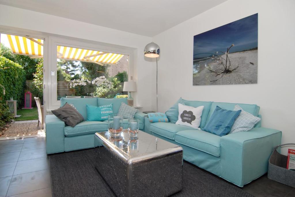 ein Wohnzimmer mit blauen Sofas und einem Couchtisch in der Unterkunft Ferienhaus Westhüs in Tinnum