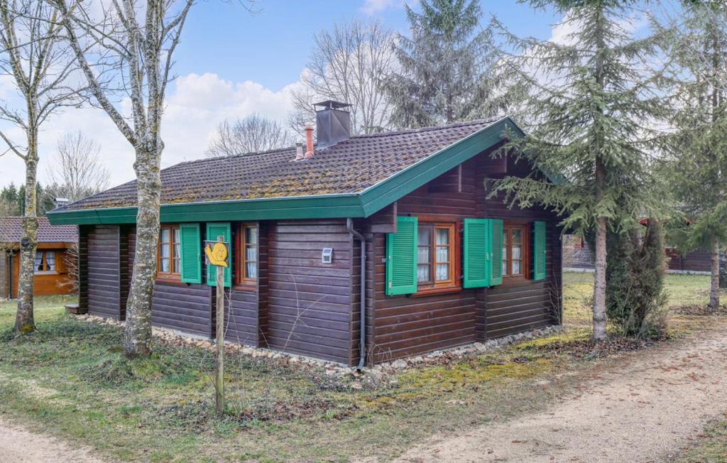 Cette petite maison en bois est dotée de volets verts. dans l'établissement Ferienhaus Neckar 108, à Hayingen