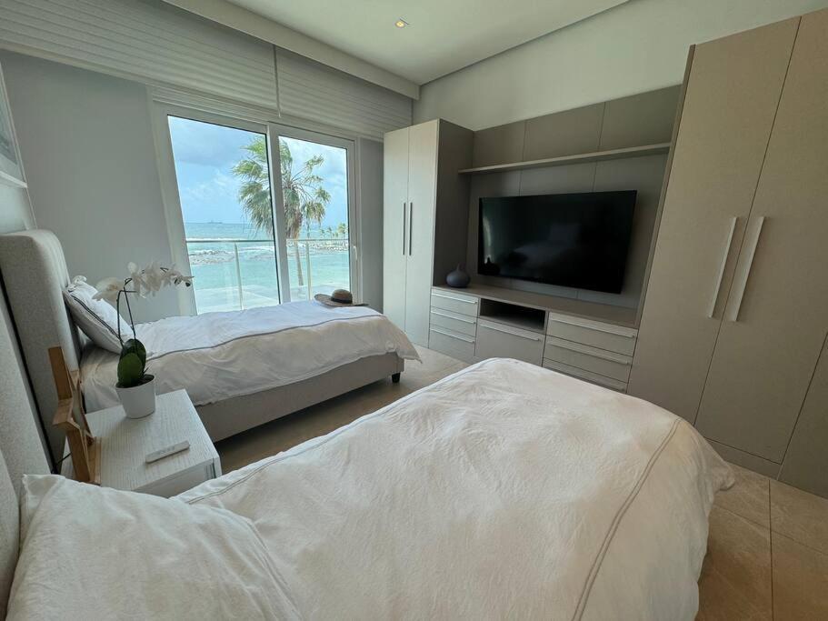 a bedroom with two beds and a flat screen tv at Paraíso Frente al Mar en Playa Escondida in María Chiquita