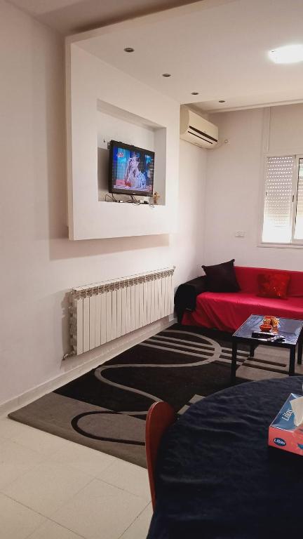 uma sala de estar com um sofá vermelho e uma televisão de ecrã plano em Kalthoum em Chott Meriem