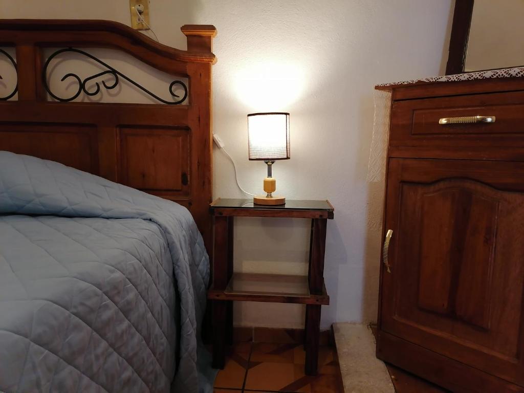 um quarto com uma cama e uma mesa com um candeeiro em Oaxaca's treasures em San Felipe del Agua