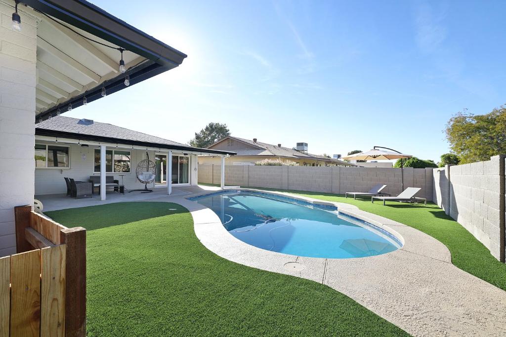a backyard with a swimming pool and grass at Pegasus - Modern Tempe Getaway with Pool & Game Room in Tempe