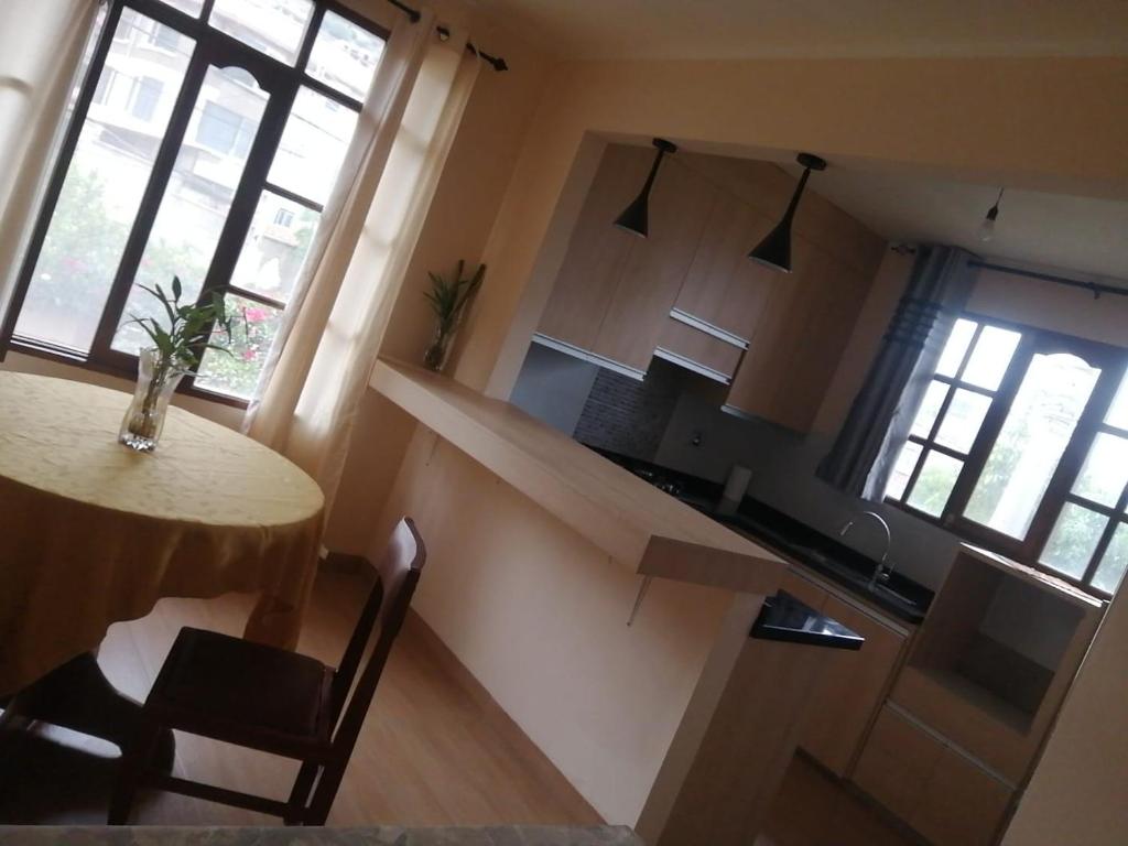 eine Küche mit einem Tisch und einem Tisch sowie eine Küche mit Fenstern in der Unterkunft Moderno in Cochabamba