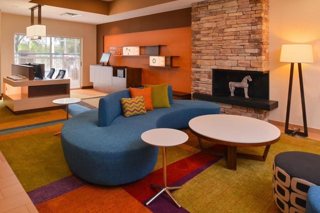 a living room with a blue couch and a fireplace at Fairfield Inn Orlando Airport in Orlando